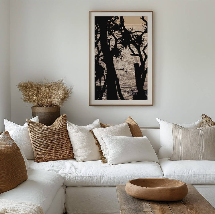 Cabarita Beach pandanus palm fine art print in a timber frame displayed above a white sofa in a cozy neutral living room.