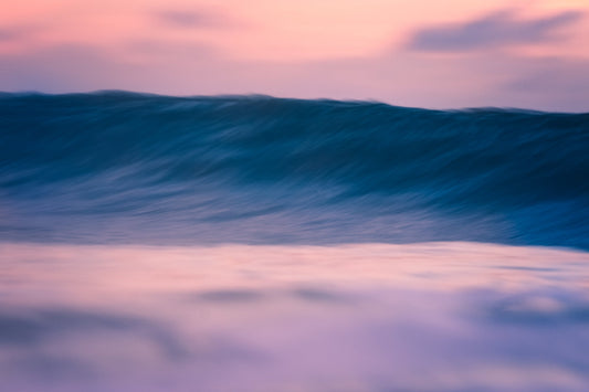 Wave in the ocean with a pink and purple sky