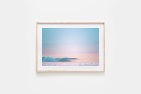 Framed artwork of a wave barrelling with a pastel sky on a white wall