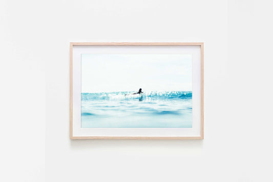Framed artwork of a surfer paddling by in the ocean surrounded by sea sparkles and water textures