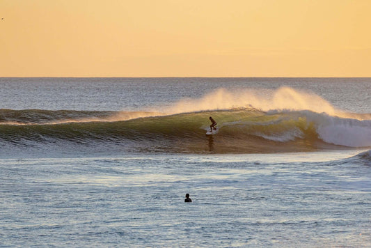 surfer at sunset in wave, almost getting barrelled