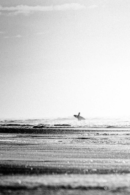 Lone surfer walking toward surf on Central American coast, black and white surf photography print