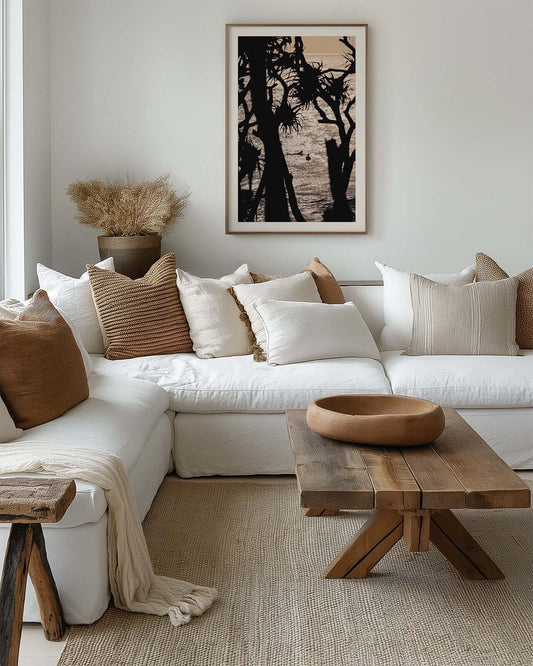 Cabarita Beach pandanus palm fine art print in a timber frame displayed above a white sofa in a cozy neutral living room.