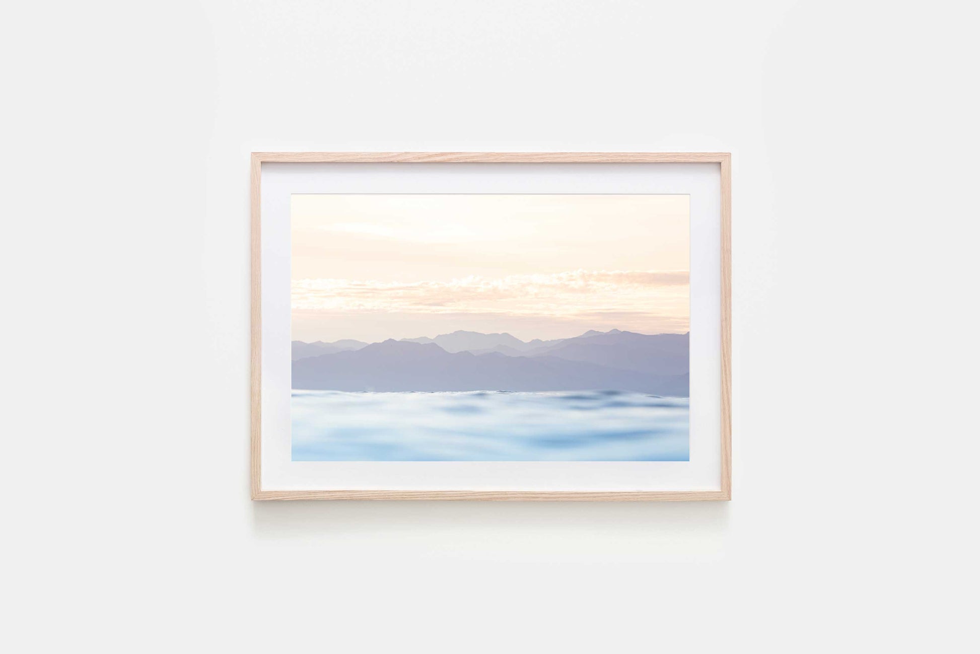 image of a soft pastel sunrise over the mountains and the ocean framed in a natural timber frame