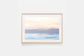 image of a soft pastel sunrise over the mountains and the ocean framed in a natural timber frame