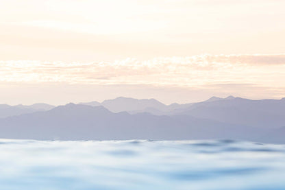 image of a soft pastel sunrise over the mountains and the ocean