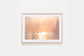 Framed Surfing print of a dreamy sunset over the ocean with surfers silhouetted in the warm light.